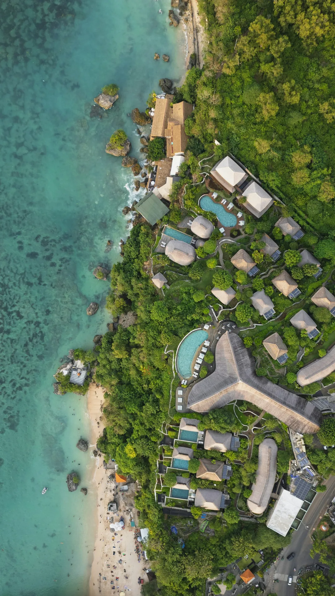 Resort villas and pools beside a clear tropical shoreline